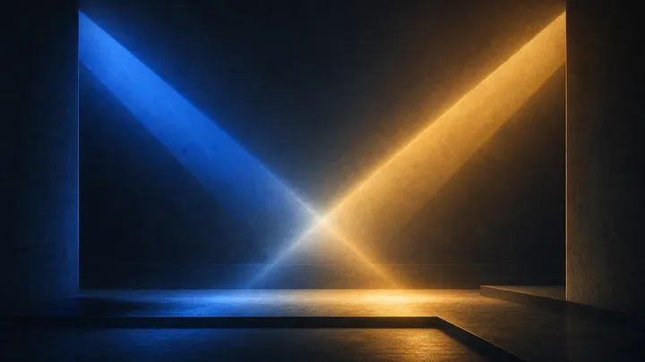 Dos haces de luz que se cruzan sobre un escenario en penumbra: uno cobalto que se atenúa, otro ámbar que asciende, sin figuras ni rostros.